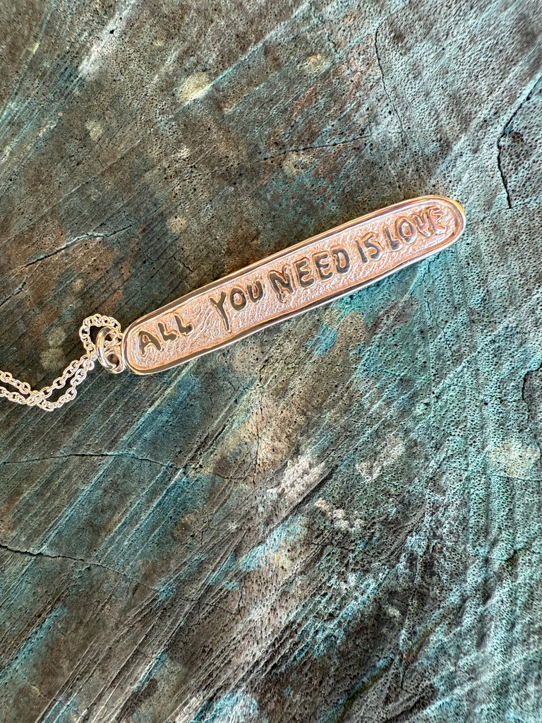 Sterling silver bracelet with 'All You Need Is Love' engraving on a textured background
