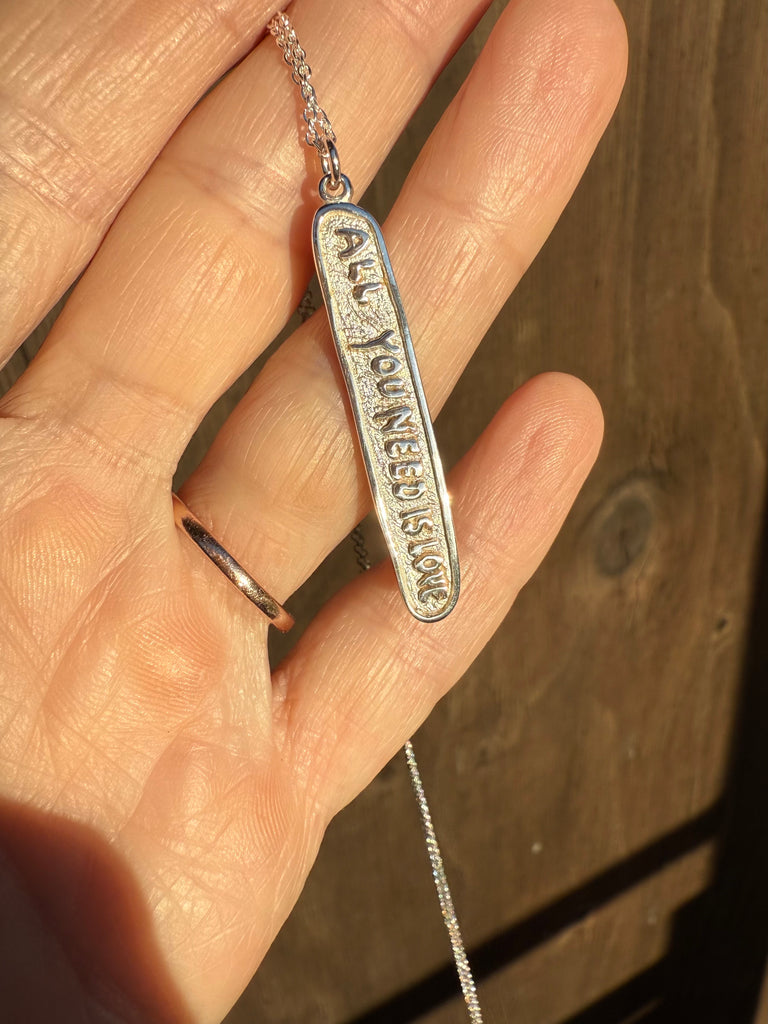 Silver necklace with pendant on a hand against a wooden background