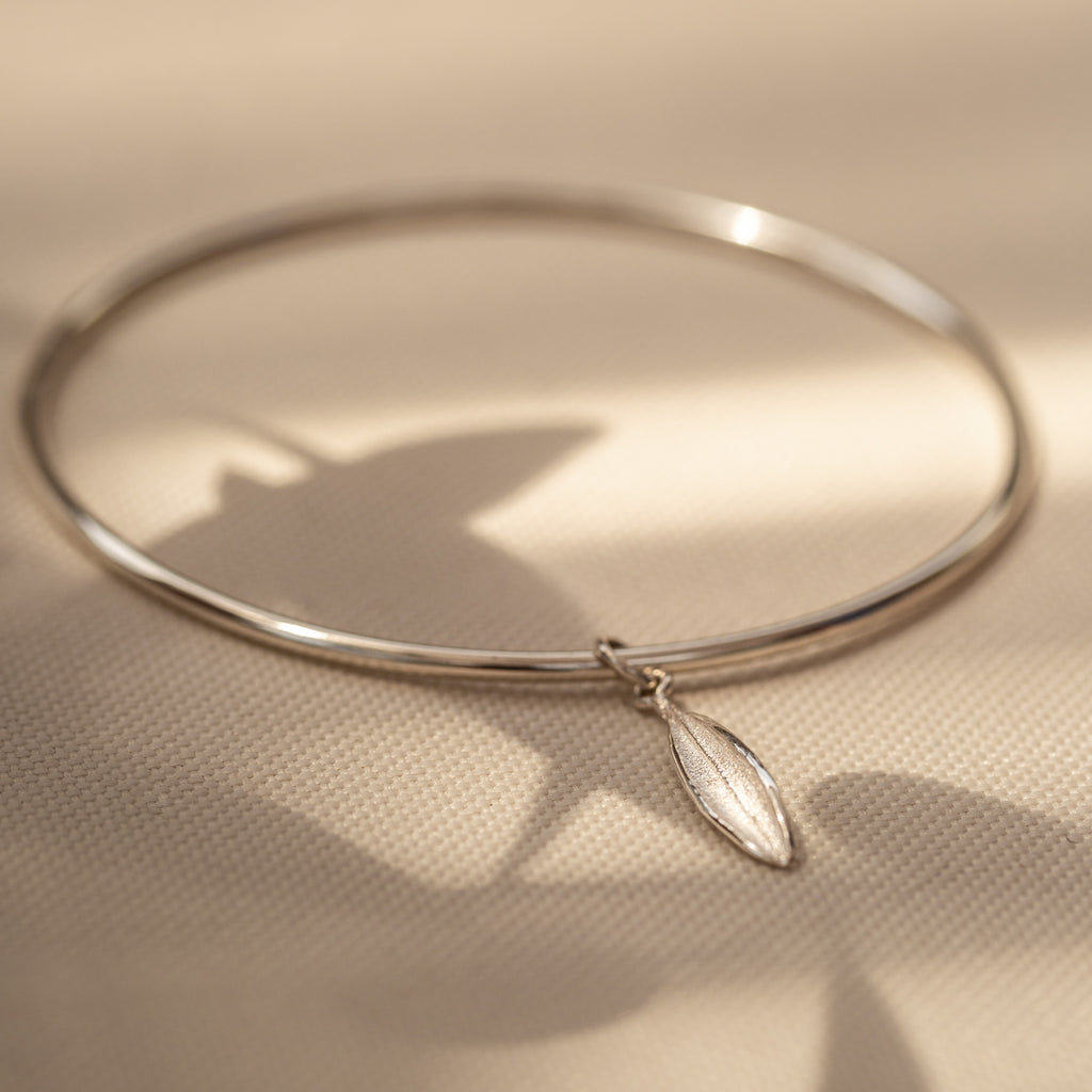 Small sterling silver olive lead charm on plain sterling silver bangle.
