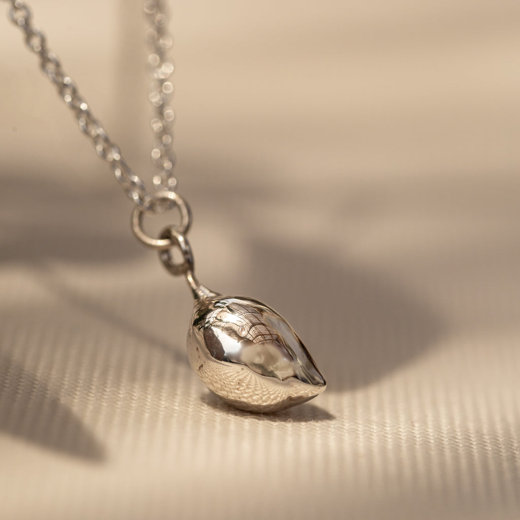 Close up of sterling silver olive pendant on chain.