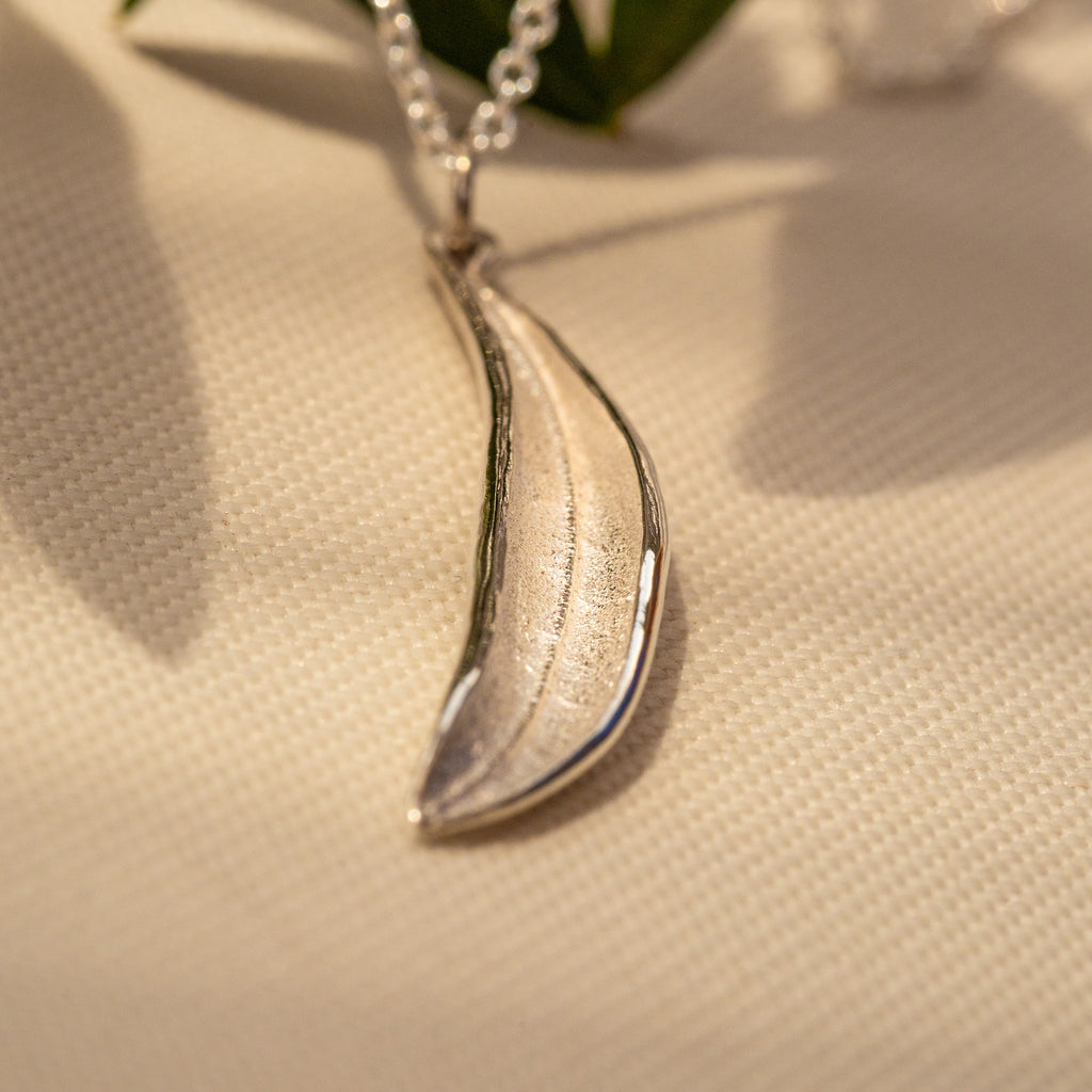 Close up of sterling silver olive leaf pendant on cable chain.