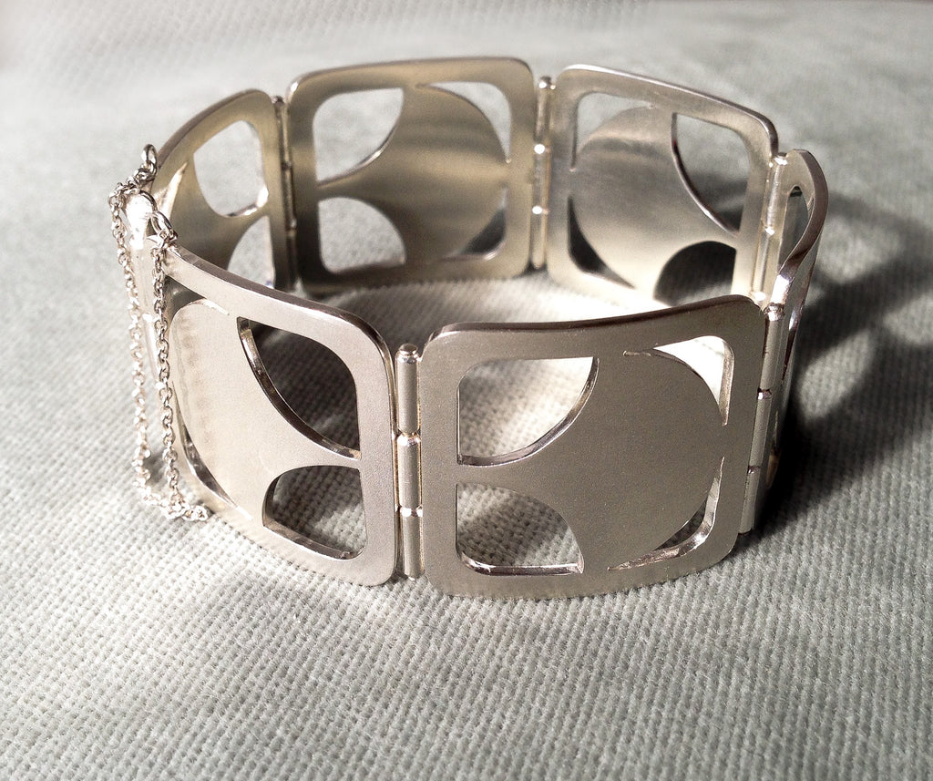 Handmade sterling silver hinged panel bracelet.  Each of the six panels has a cut out Art Deco shape which is repeated on each panel.