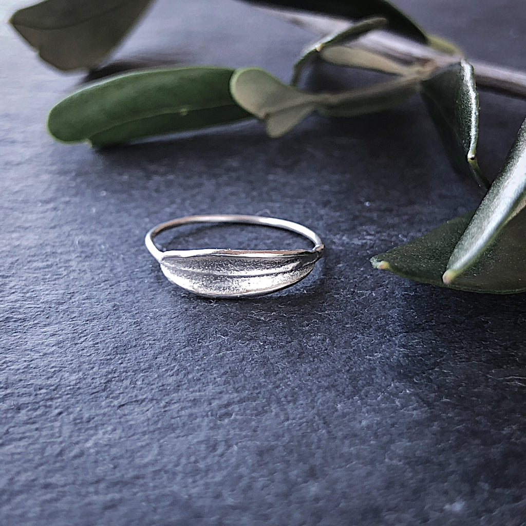 Sterling silver dainty handmade olive leaf ring with olive leaves on dark background.