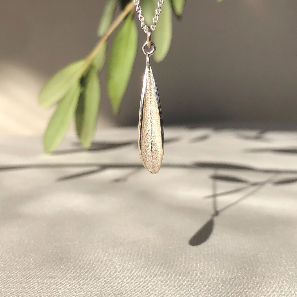 Handmade sterling silver picual olive leaf pendant hanging on a fine sterling silver cable chain.